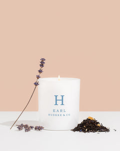 Huskke & Co Earl candle with lavender sprigs and tea leaves, showcasing the Earl candle notes of calming lavender and bergamot.