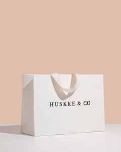 Huskke & Co candle gift bag in an elegant white design with soft fabric handles, perfect for presenting a luxury candle gift.